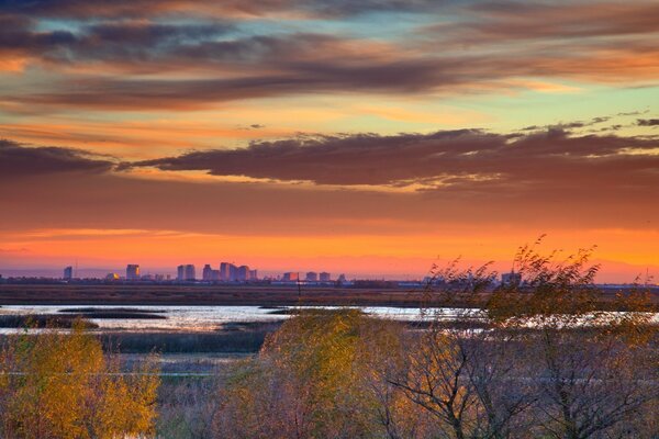 Amanecer de otoño con vistas a un lago pantanoso y una ciudad en la distancia