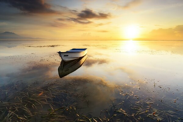 A boat on the water that mirrors the sky