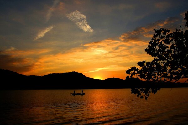 Sunset over the mountains, people on a boat