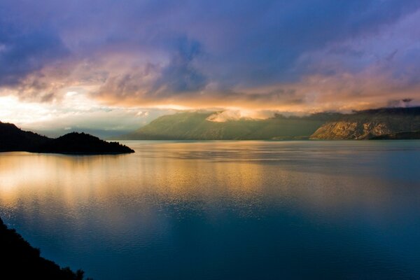 Puesta de sol sobre el agua. Reflejo de la puesta de sol en el agua. Agua tranquila. Oscurece