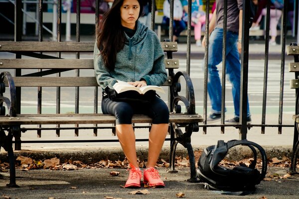 Ragazza seduta su una panchina vicino alla recinzione