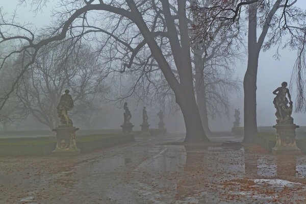 Autumn misty park with statues