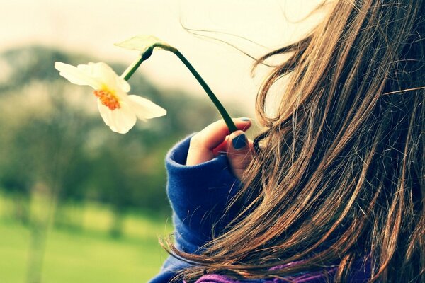 The girl holds a flower in her hand