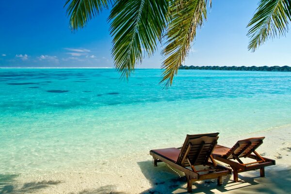 A beach with blue water and a chaise longue