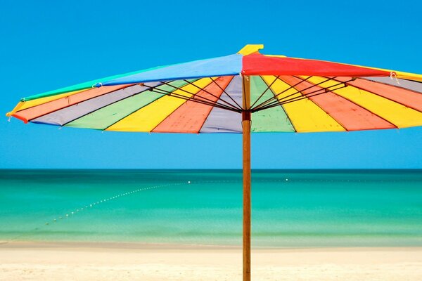 Regenbogenschirm am Strand im Meer