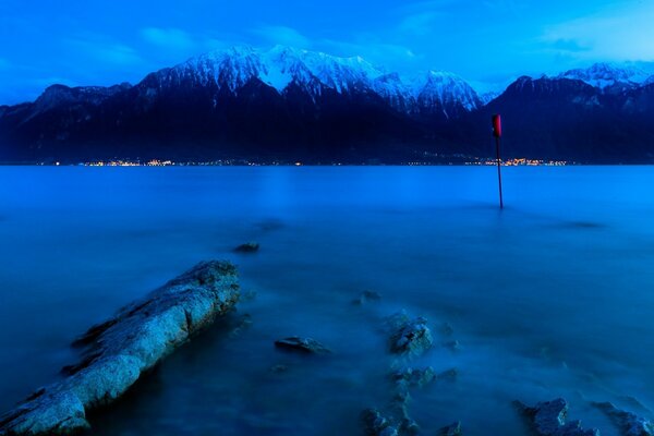 Crepúsculo en el lago. Picos de montaña en la nieve