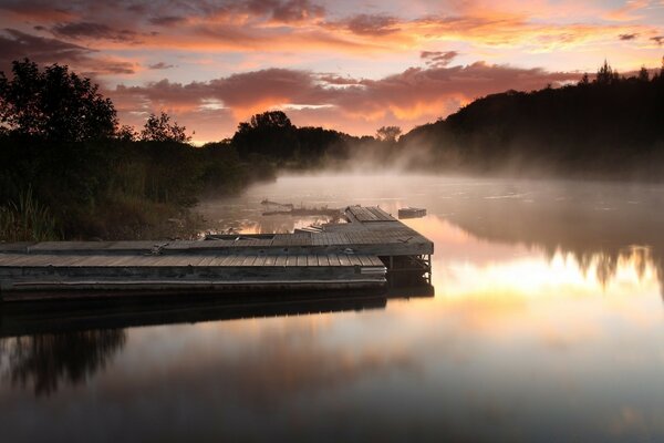 Molo sul lago in un alba nebbiosa