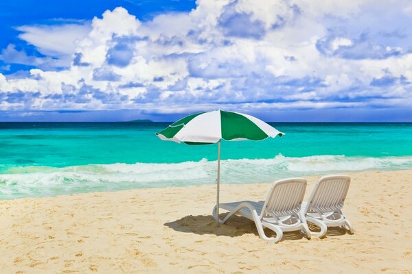 Шезлонги и зонтик на песчаном пляже