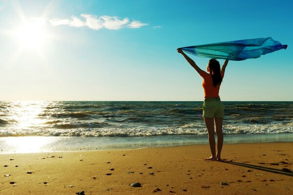 Fille avec paréo sur la plage. Sable jaune et lever du soleil