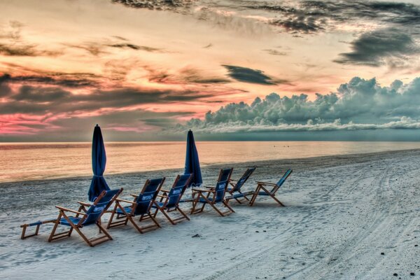 Sedie a sdraio sulla spiaggia di sabbia al tramonto