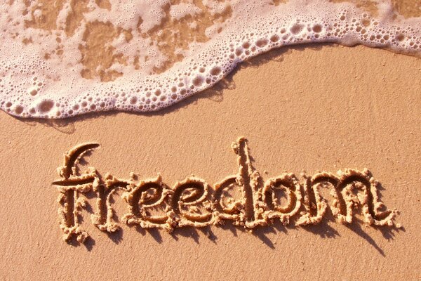 The inscription freedom in English on the sand