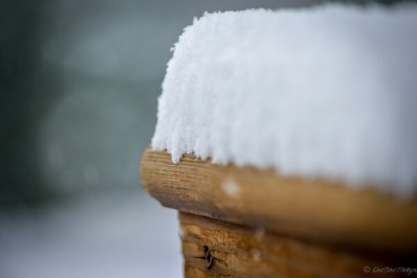 Auf dem Holz ist weißer Schnee verschwommen