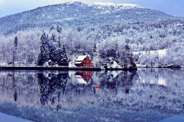 A lake house on the background of a winter landscape and a mountain