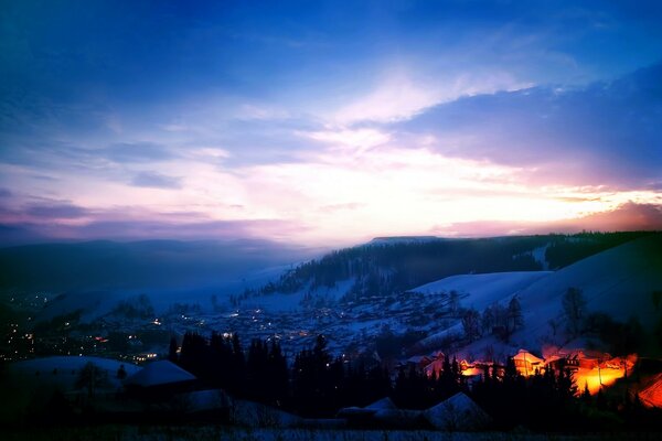 Amanhecer em uma cidade entre montanhas cobertas de neve