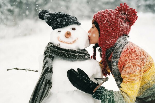 Mädchen küsst Schneemann im freien