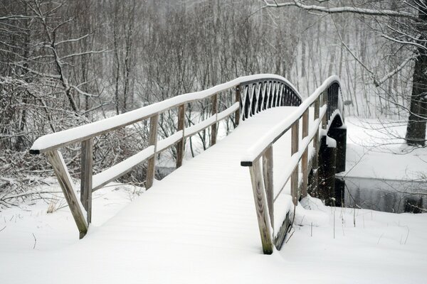 A snow-covered bridge over a small river