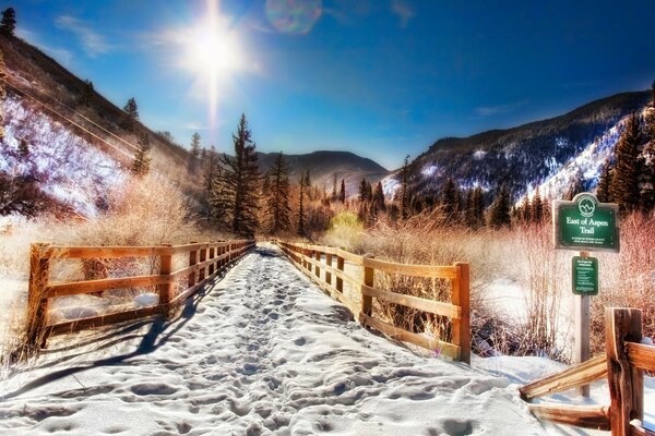 A snow-covered road in the mountains surrounded by a fence