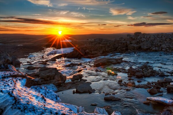 Puesta de sol sobre el paisaje de invierno con piedras