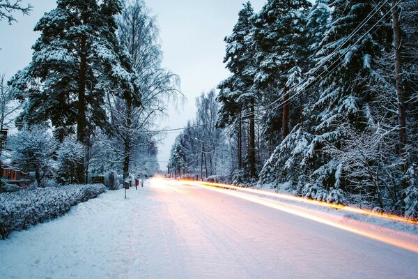 Winterstraße und Lichter von vorbeifahrenden Autos