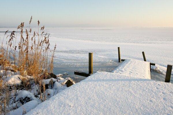 Snow-covered parapet on the background of frozen water