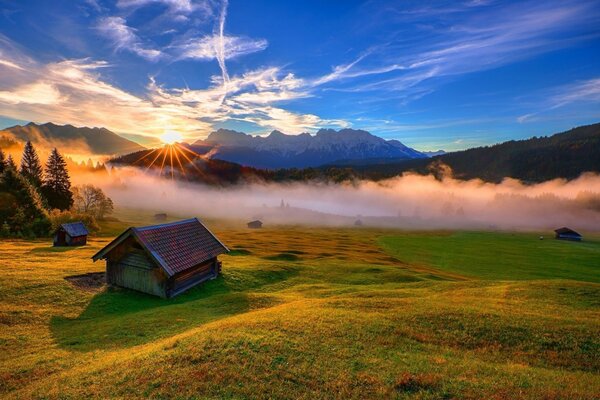 A wooden house on a meadow in the morning sun