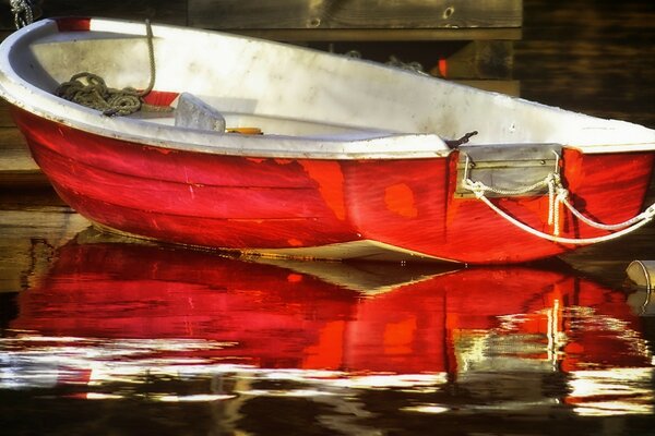 Red boat on the pier and reflection in the water