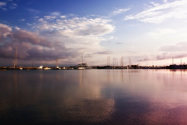 Silhouettes of yachts on the embankment at sunset