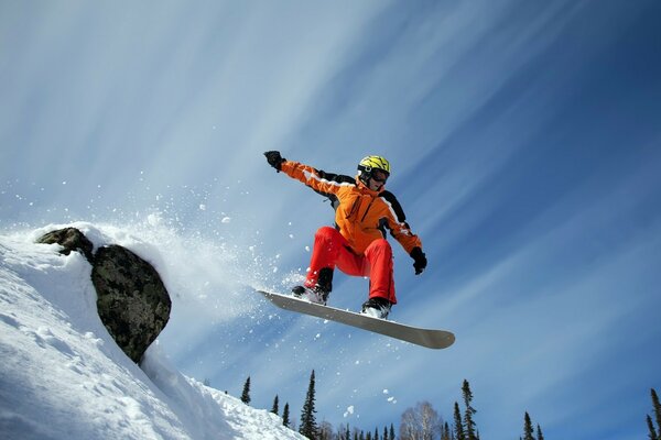 Snowboardcu gökyüzünün arka planına karşı trambolinden atlıyor