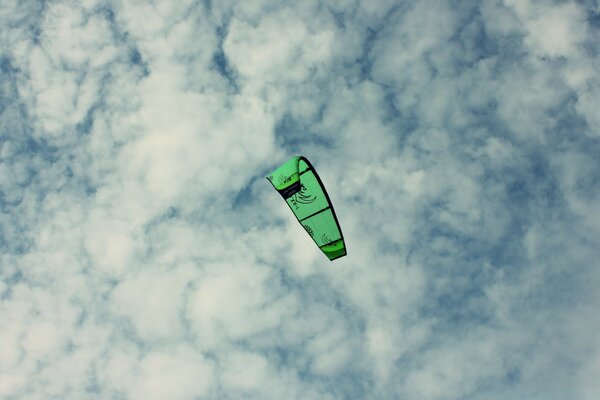 The paraglider is green in a cloudy sky