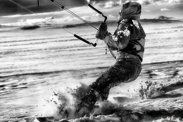 Black and white photo. A man rides on a snowboard in the snow