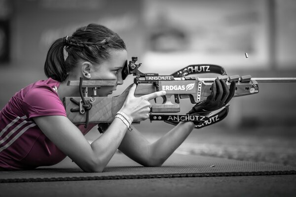 Sportlerin schießt mit Gewehr in rosa T-Shirt