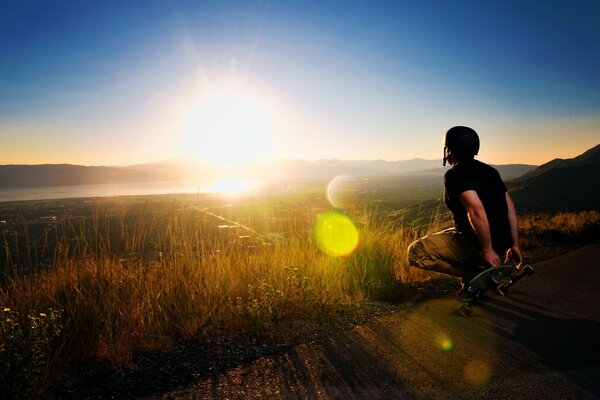 Uomo seduto con uno skate al tramonto