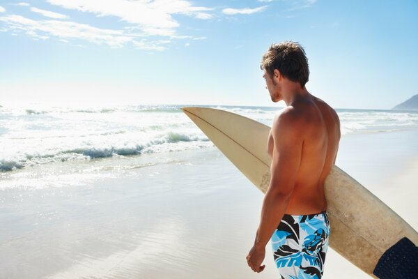 A man with a surfboard in his hand on the seashore