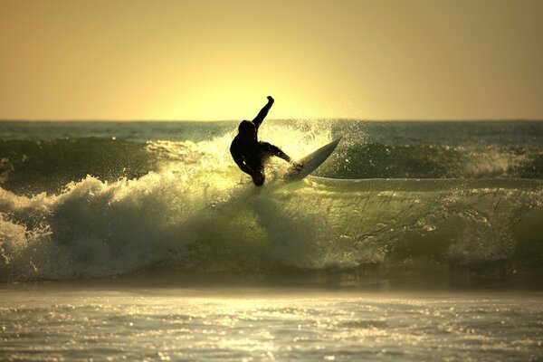 Surfer overcomes waves against the background of sunset