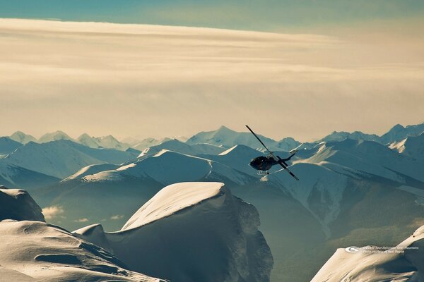 The helicopter is flying among the snowy mountain peaks