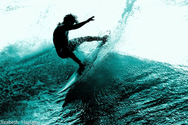 Young surfer cuts blue waves