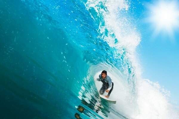 Surfer rolls under a wave on a board