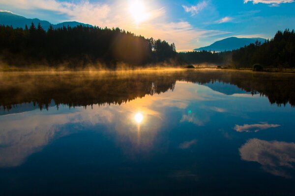 Morgendämmerung an einem frostigen See inmitten des Waldes