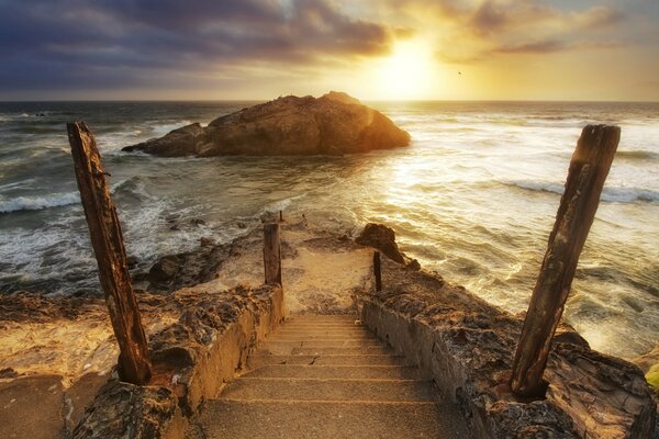 Straining bajando las escaleras hacia el mar durante la puesta del sol