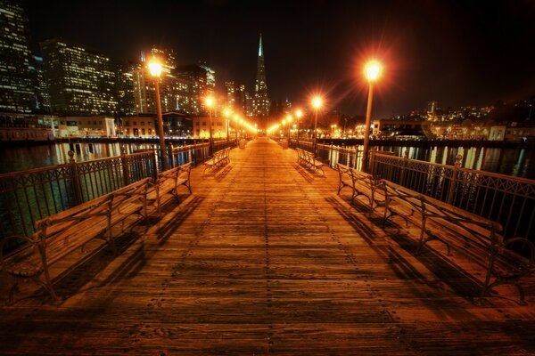 The wooden bridge is illuminated by many lanterns