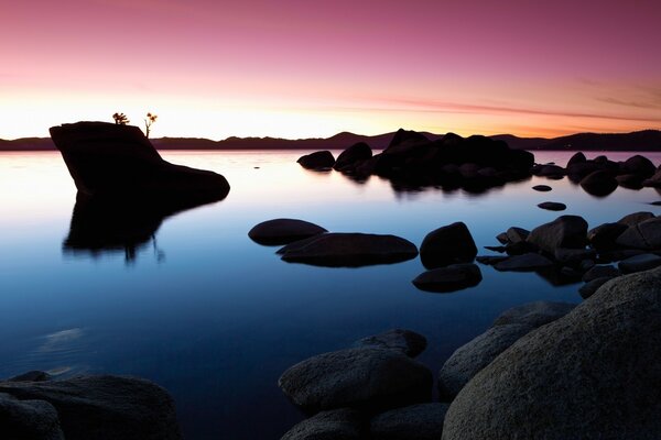 Puesta de sol en América contra el agua y las rocas