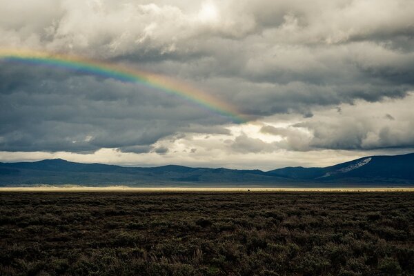 Schöne Regenbogenlandschaft am düsteren Himmel