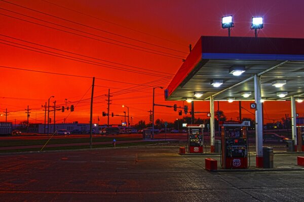 Gasolinera desierta en medio de una puesta de sol carmesí