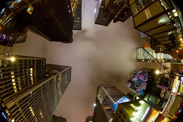 No centro, um céu noturno enevoado cercado por arranha-céus em luzes