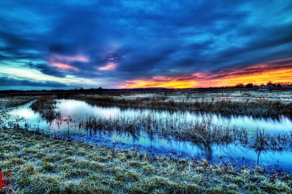 Nubes de colores en el fondo de la hierba y el agua