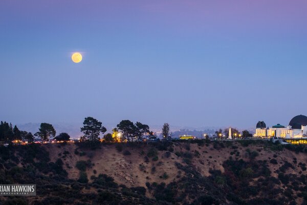 Mond am Himmel auf dem Hintergrund der Abendstadt