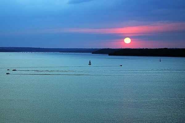 Puesta de sol en el agua, barcos flotando