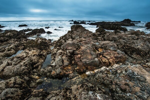 Praia rochosa contra o céu sombrio