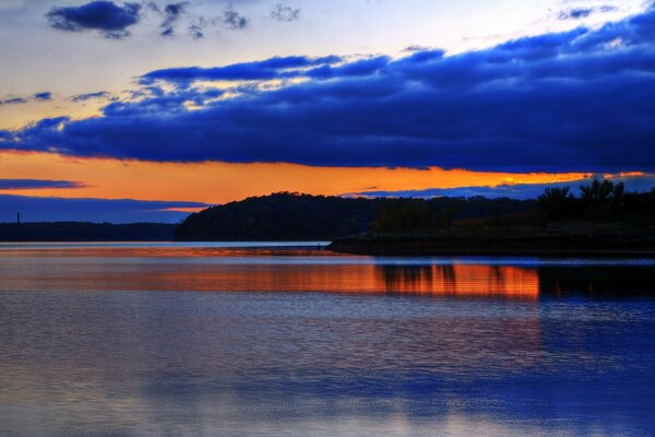 Bright sunset on the river with blue clouds