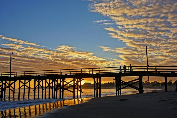 Sunset on the sea on the background of the beach and the bridge